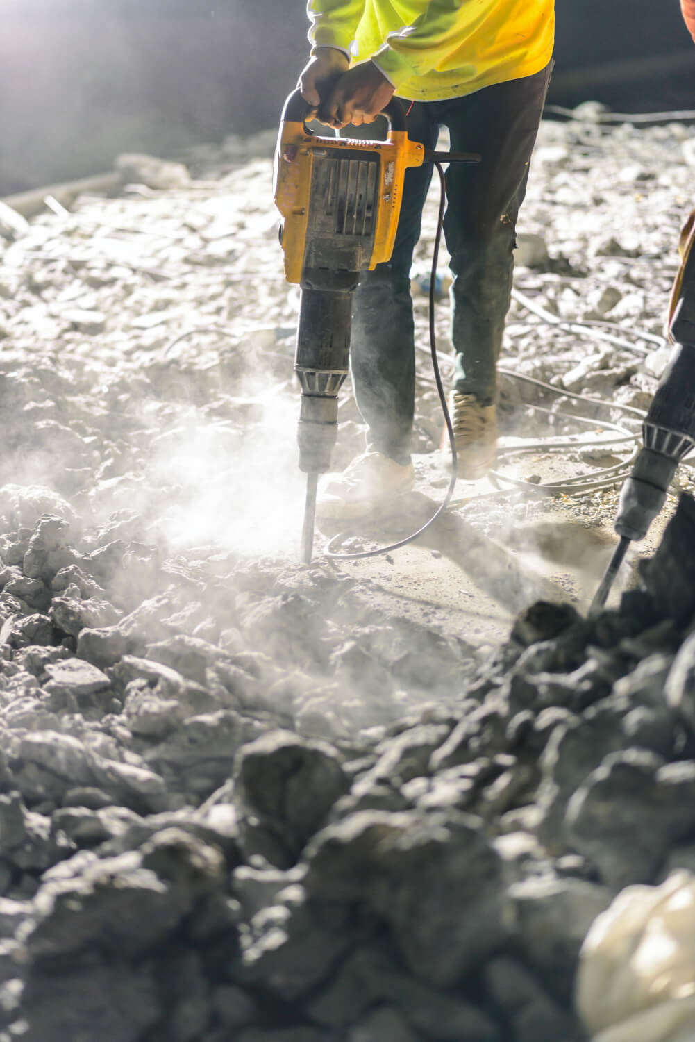 Bauarbeiter mit Presslufthammer in Bauschutt