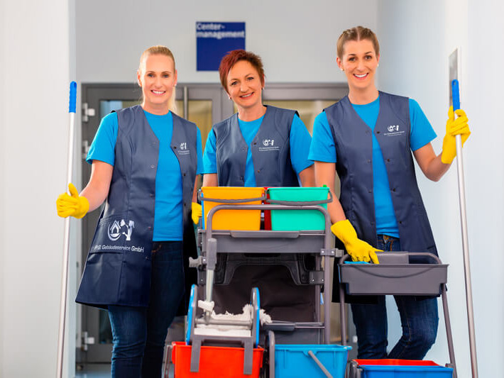 Drei Reingungskräfte mit Putzwagen